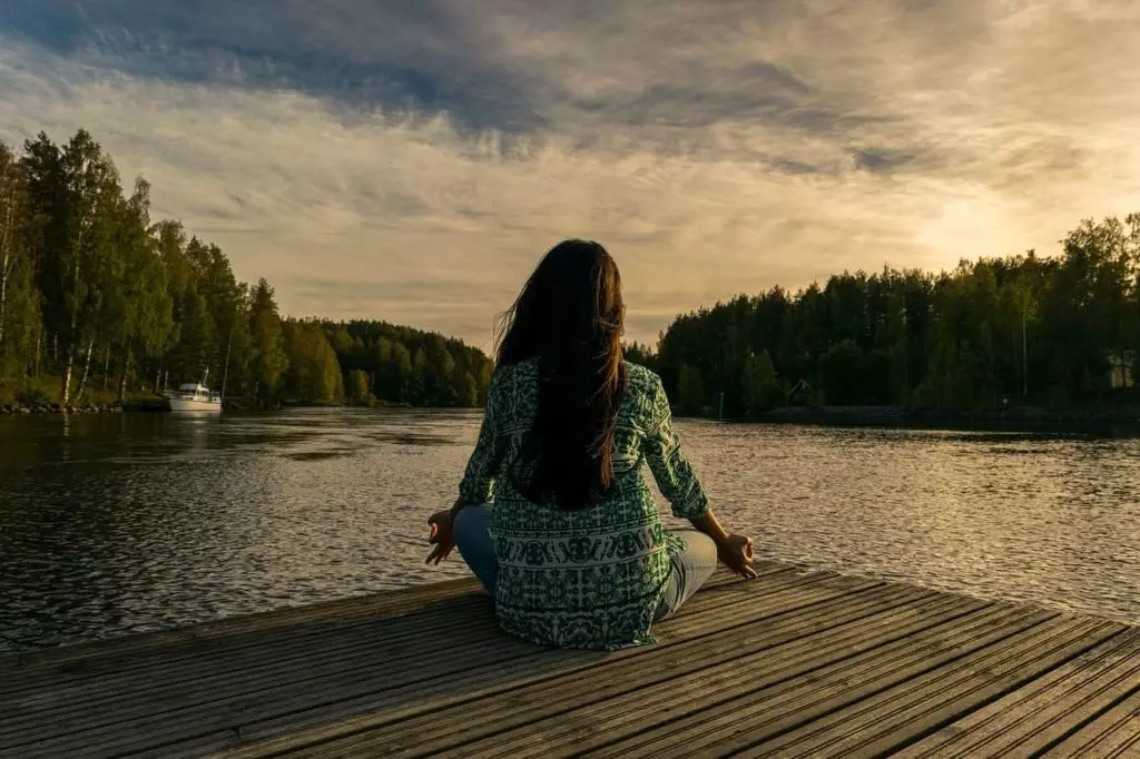Weniger arbeiten und mehr leben - Frau macht Yoga am See